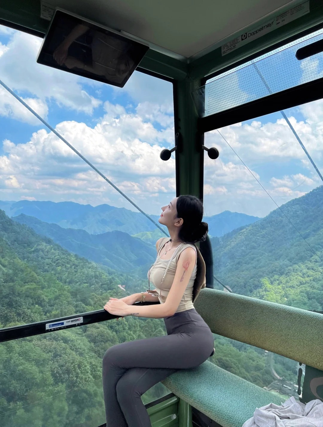 Du kh&aacute;ch ngồi trong cabin c&aacute;p treo ngắm cảnh n&uacute;i.