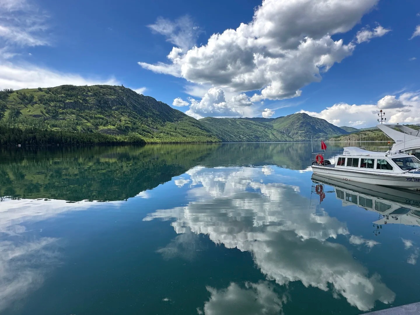Toàn cảnh Hồ Kanas soi bóng núi tuyết và rừng Taiga, mặt nước xanh ngọc bích phẳng lặng như gương giữa thiên nhiên hoang sơ và hùng vĩ.
