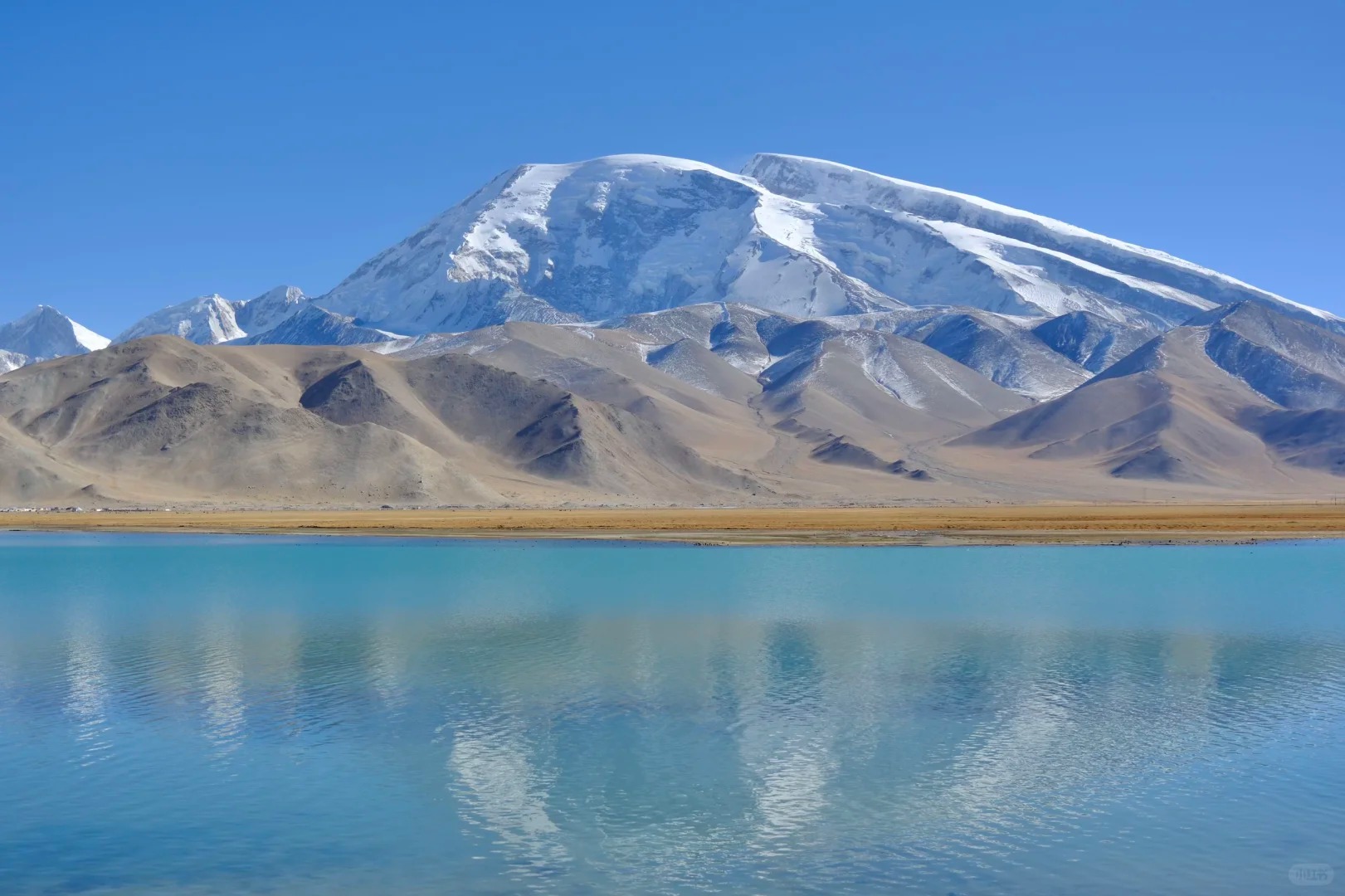 Hồ Karakul xanh thẳm soi bóng núi tuyết Muztagh Ata sừng sững phía xa.