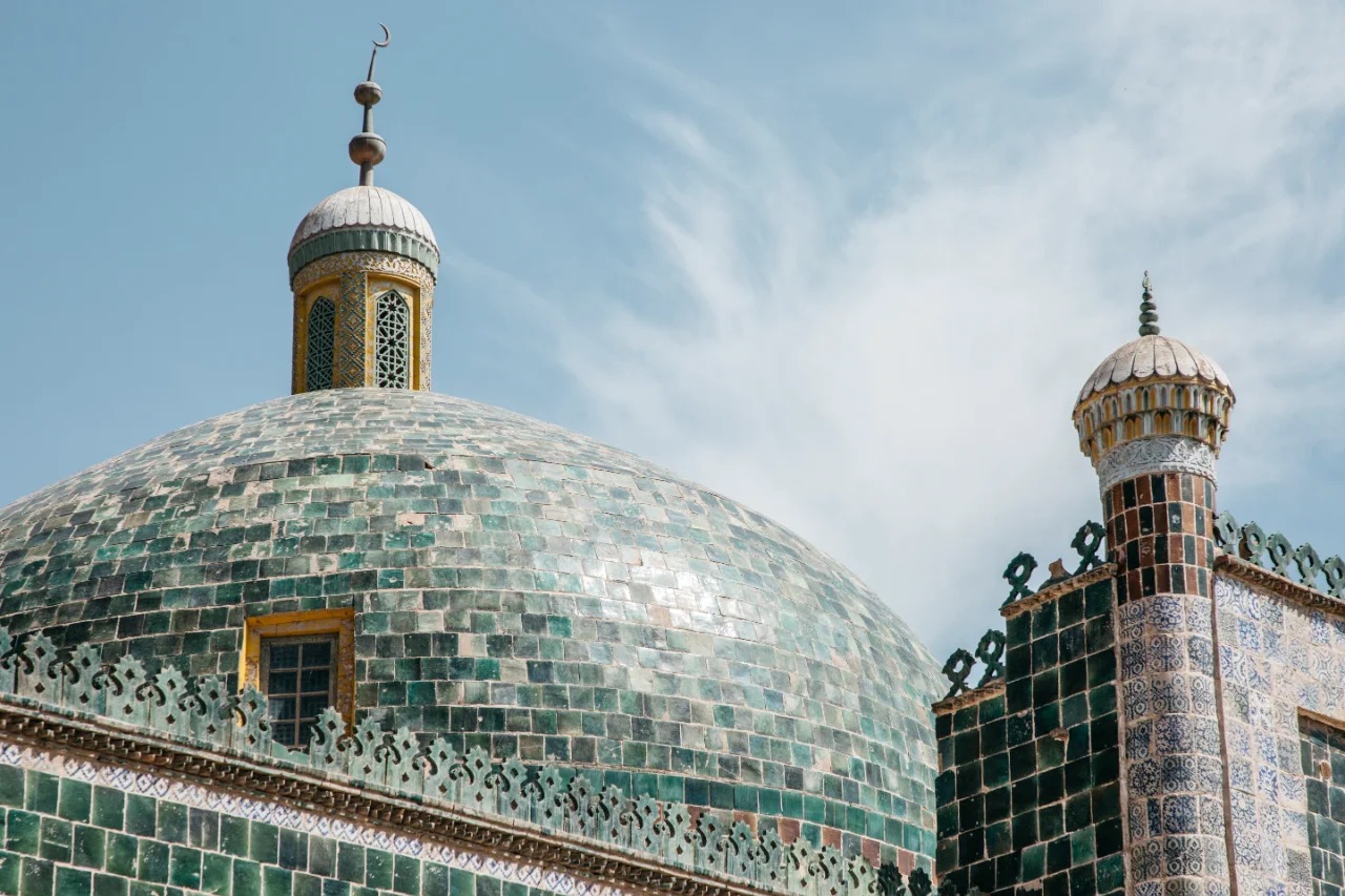 Mái vòm xanh ngọc của Lăng Hương Phi nổi bật giữa nền trời xanh và cây xanh rợp bóng.