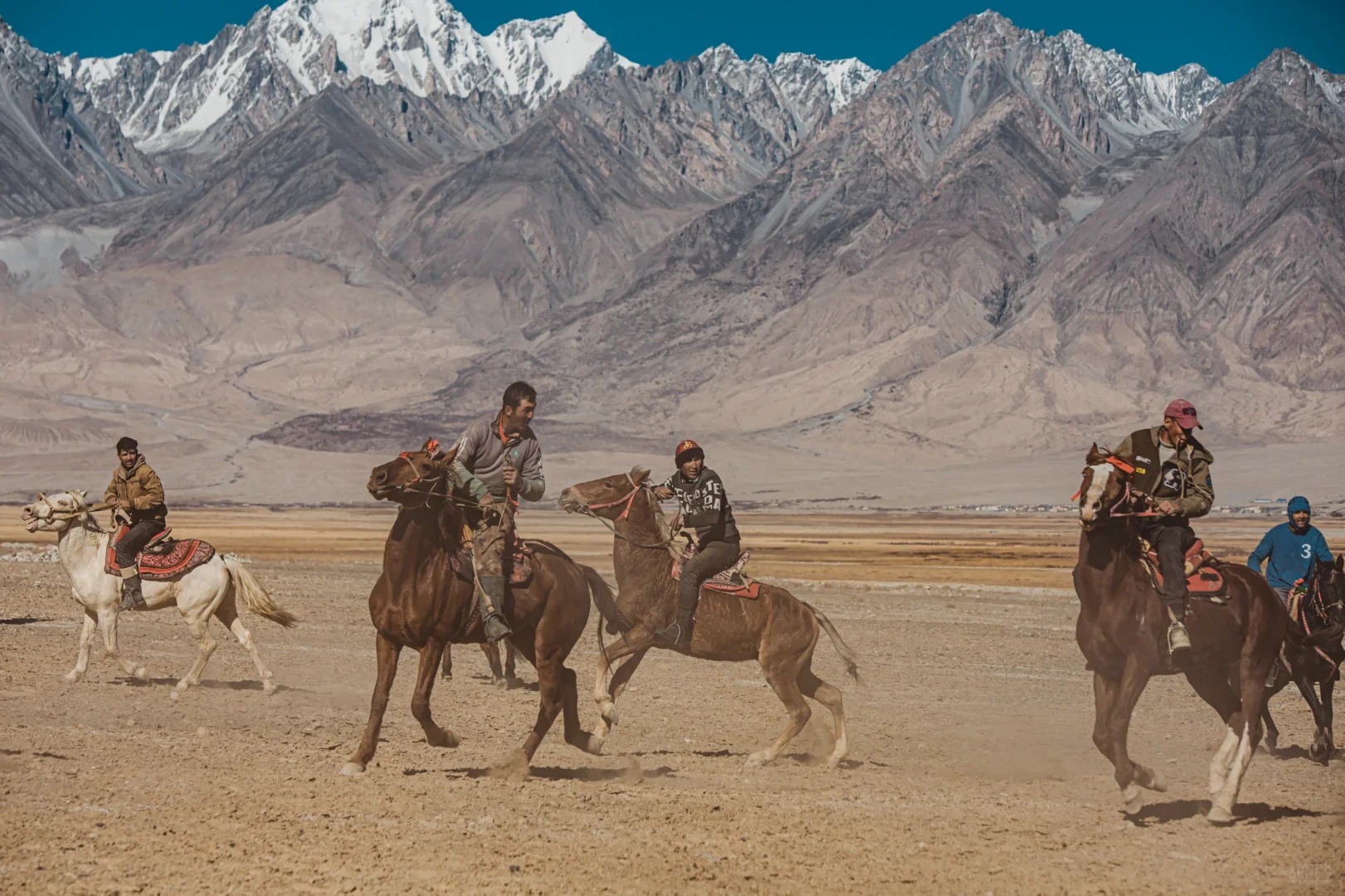 Người dân tajik cưỡi ngựa trên thảo nguyên pamir bát ngát phía sau là dãy núi tuyết